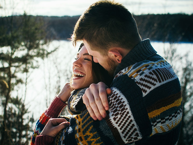 A woman hugging her boyfriend and trying not to misread the dating signs.