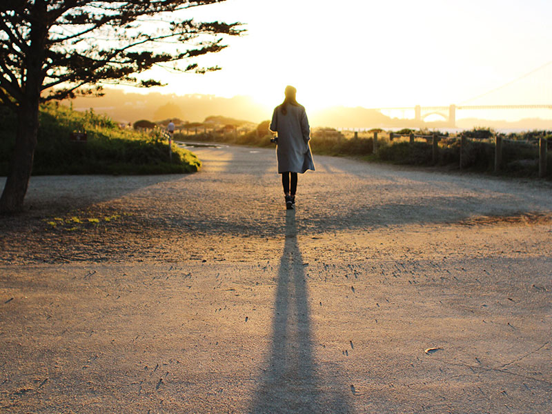 A man listening to songs about leaving someone as he walks into the sunset and away from a bad relationship.