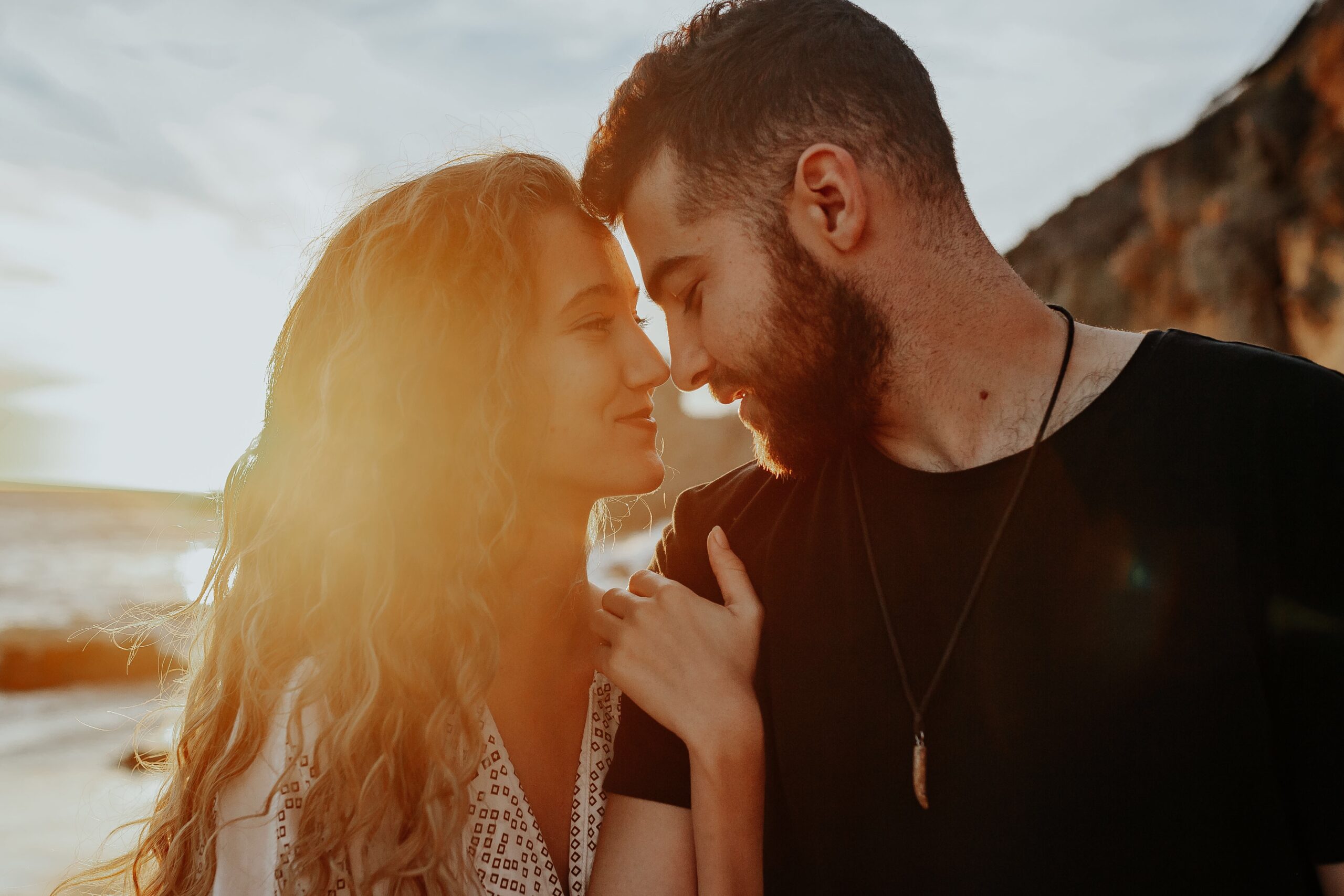 A couple in a twin flame relationship, looking into each other's eyes and souls on the beach at sunset.