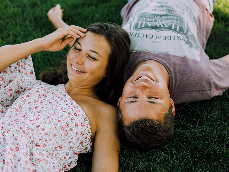 A guy who used one of these creative first date tips, laughing in the grass with his date.