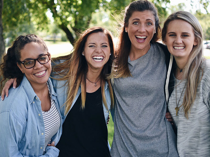 Four girls who are different types of friends, all hugging and laughing together.
