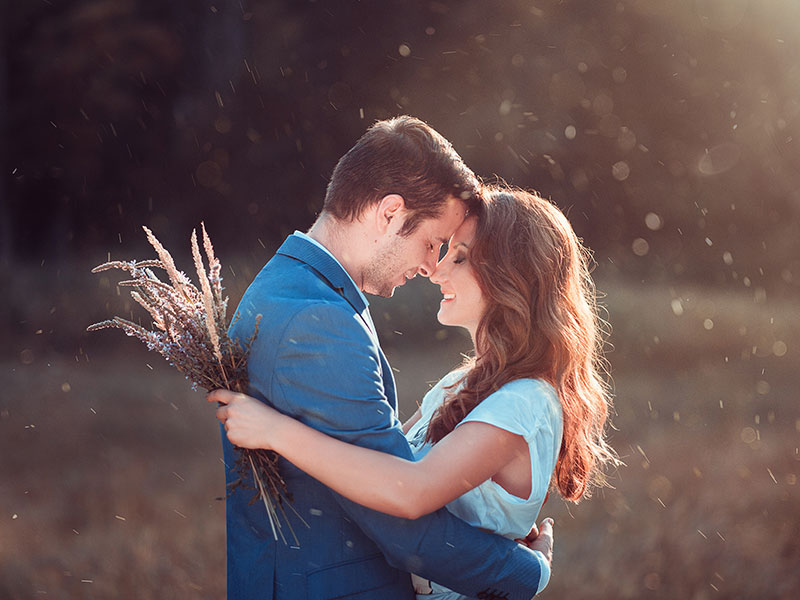 A couple who knows what is romance, hugging in the sun in a field.