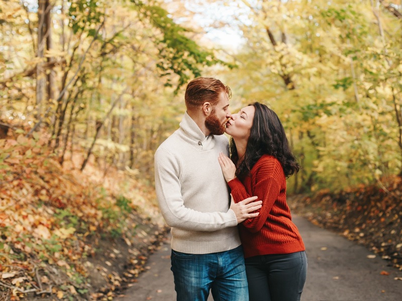 Couple taking older woman younger man relationship advice and kissing in a forest