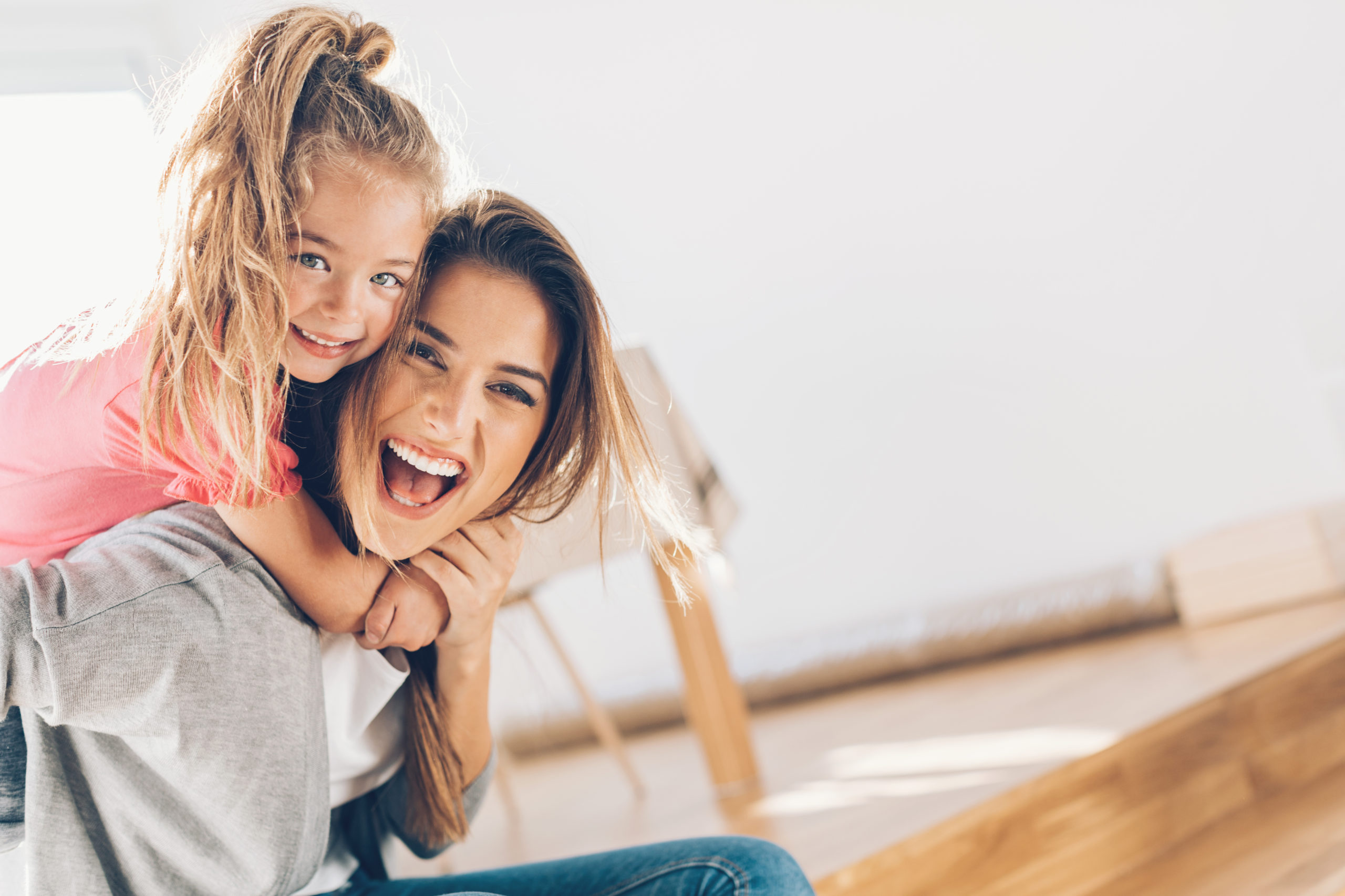 single mom laughing with young daughter on her back