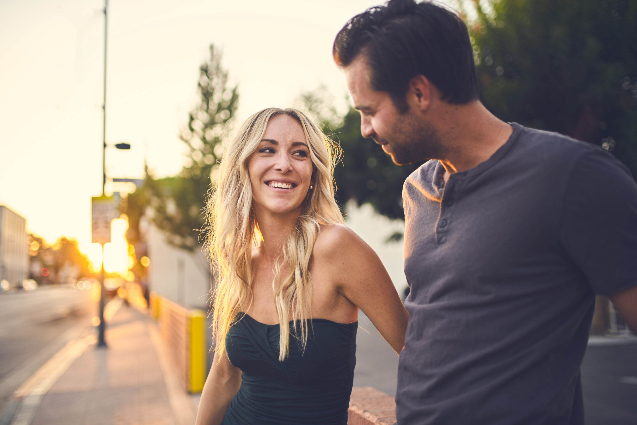 Two young, attractive Omaha singles looking into each other's eyes while holding hands and walking down the street.
